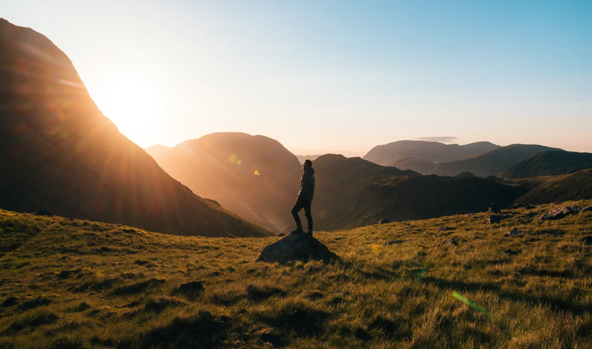 a man standing on a rocky outcrop at sunset